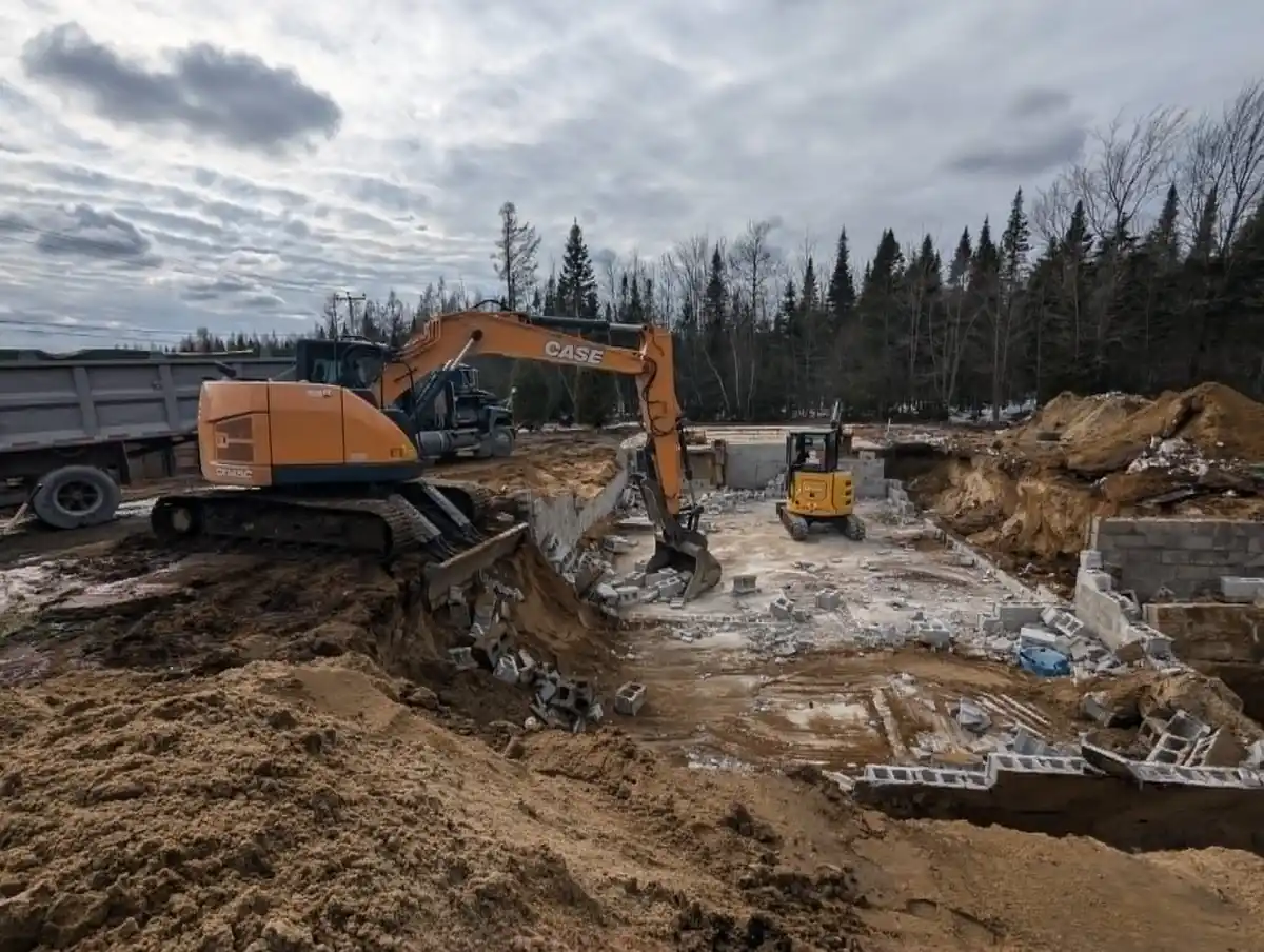 Excavatrice réalisant la démolition de murs en blocs de béton sur un chantier