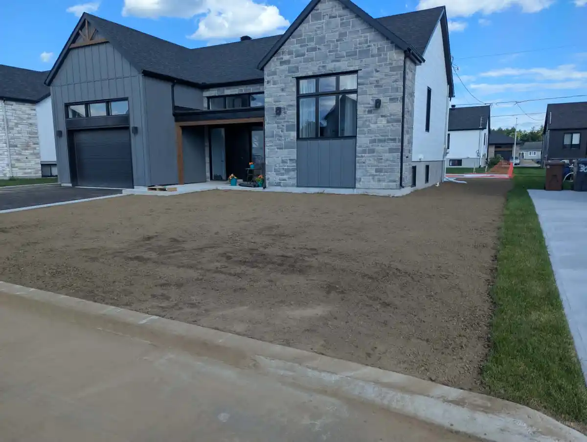 Nivellement d’un terrain résidentiel devant une maison neuve